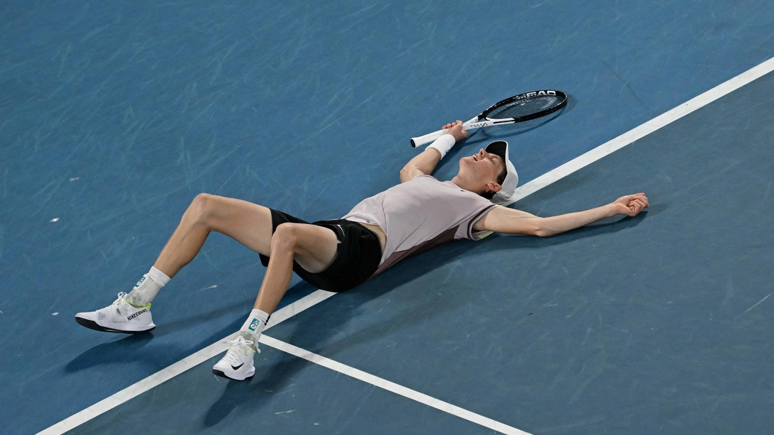 Jannik Sinner a terra, stremato, dopo la vittoria agli Australian Open 2024 (Ansa)