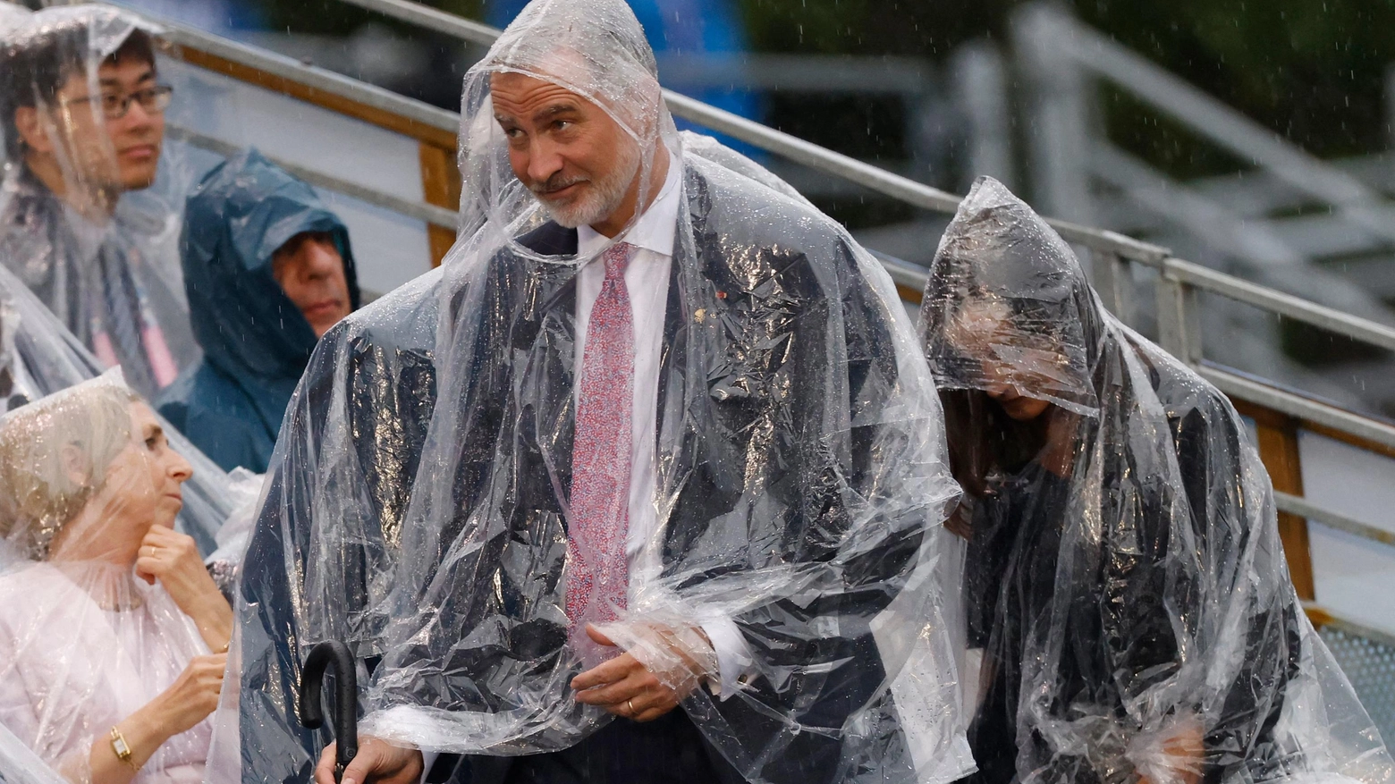 Il re di Spagna Felipe Vi e la regina Letizia con l'impermeabile per ripararsi dalla pioggia